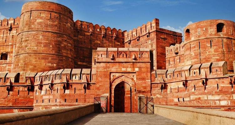 Massive red sandstone fort with detailed facade, under a clear sky.
