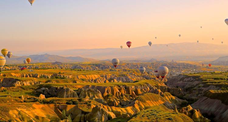 Sonnenaufgang-Panorama von Kappadokiens Feenenschlössern-Landschaft mit Dutzenden von bunten Heißluftballons