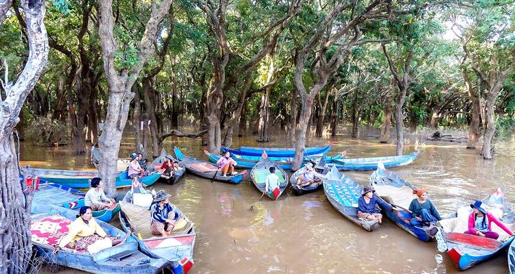 Boats with people navigating through a flooded forest area.