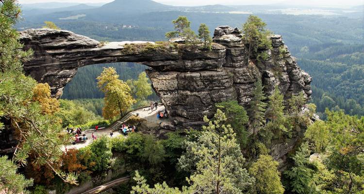 Natural rock arch bridge with people walking across.