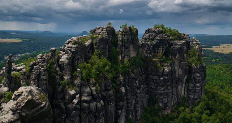 Rock formations surrounded by lush greenery under a cloudy sky.