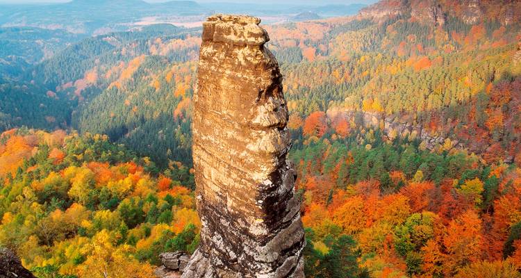 Tall rock formation surrounded by vibrant autumn foliage.