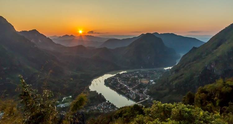 A scenic view of a river winding through mountains at sunset.