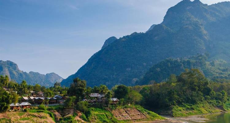 A view of a village nestled between mountains and a river.