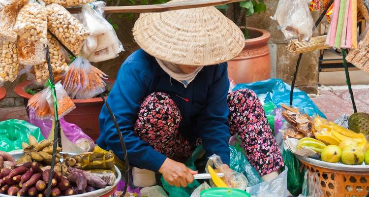 Vendor preparing produce at a market stall.