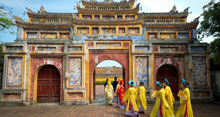 Group of people in traditional attire walking through a historic gate.