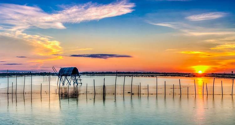 Beautiful sunset over water with a silhouette of a small structure.