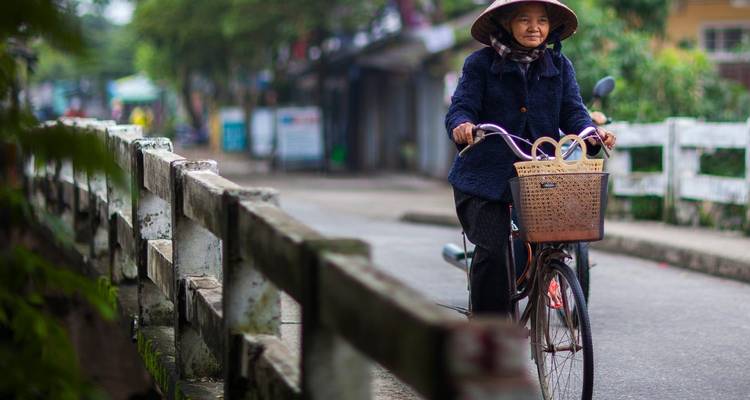 Woman riding a bicycle with a basket in a street.