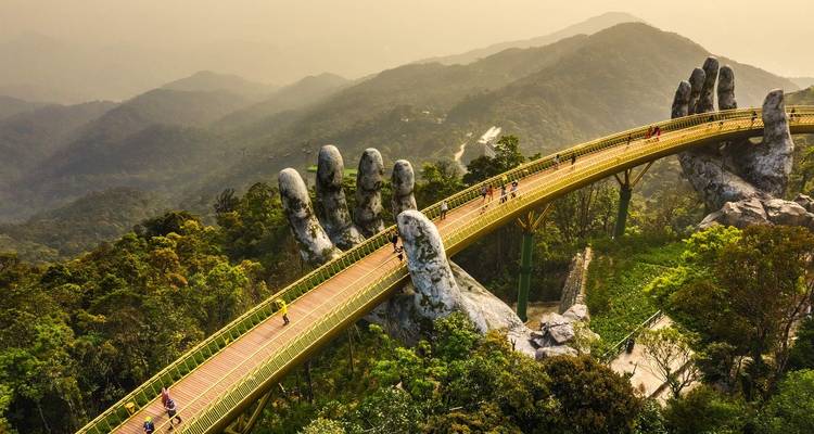 Golden Bridge with giant hands in Da Nang, surrounded by lush greenery and mist.