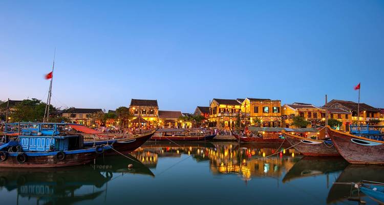 Traditional boats in harbor reflecting lights at dusk.