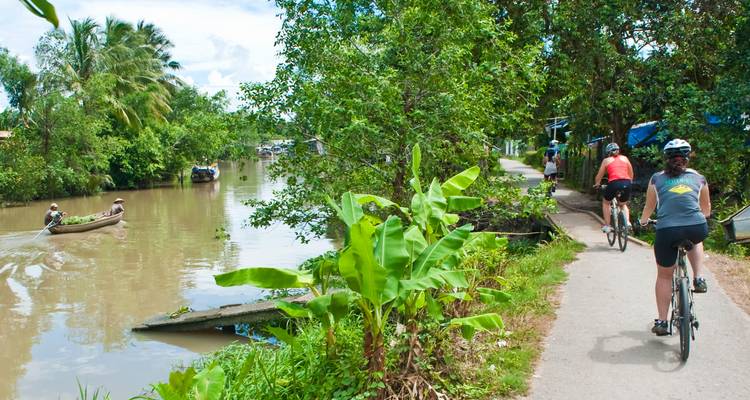 Cyclists riding along a tropical canal.
