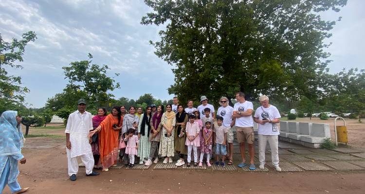 Un groupe de personnes posant ensemble à l'extérieur avec des arbres en arrière-plan.