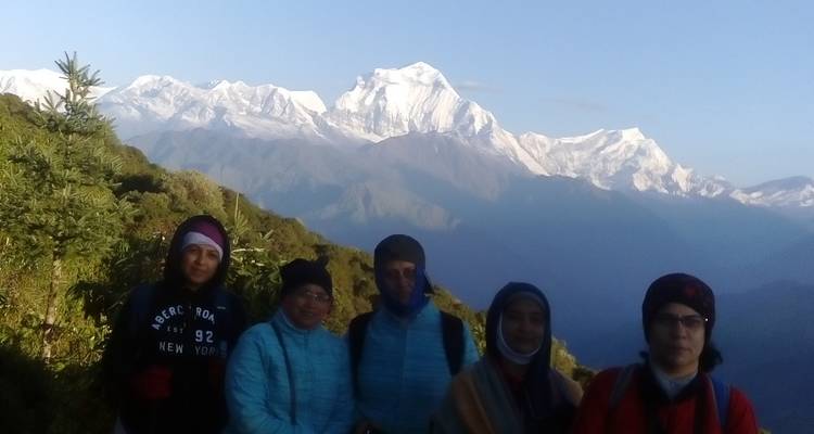 Gruppe von Menschen mit Bergen im Hintergrund bei Morgendämmerung.