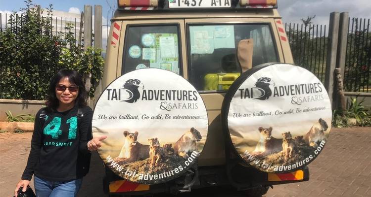 Personne debout près d'un véhicule de safari avec des housses de roues de secours.