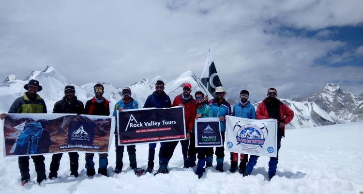 Group of people on a snowy mountain holding banners and a flag.