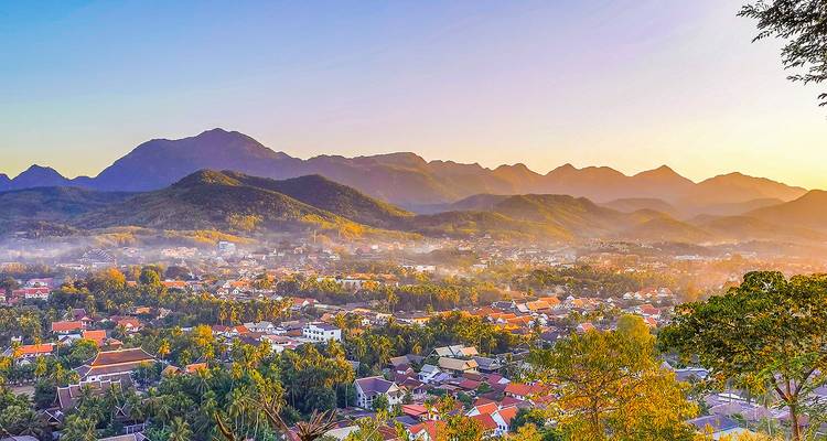 Panoramisch uitzicht op een stad omringd door mistige heuvels bij zonsopgang.