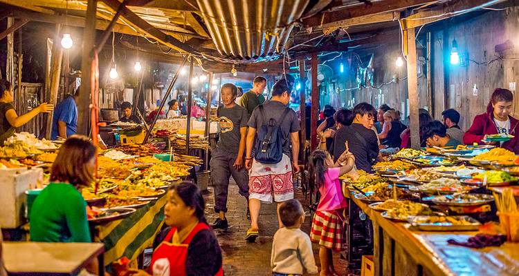 Drukke nachtmarkt met mensen en eetkraampjes.