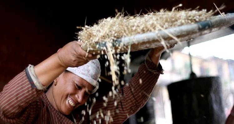 Smiling woman sifting grains.