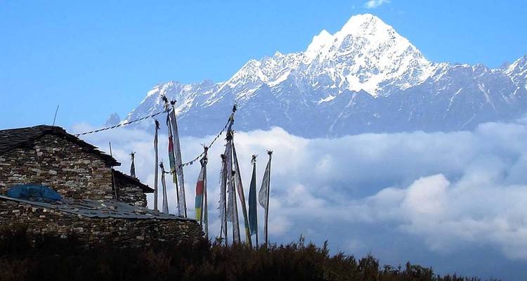 Remote mountain landscape with prayer flags and stone hut.