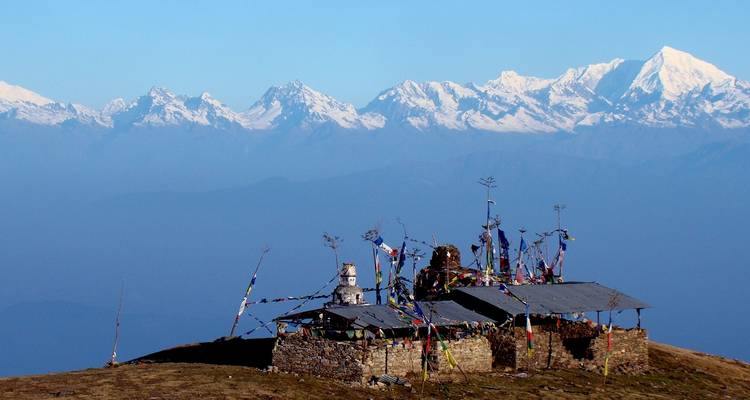 Panoramic view of snow-capped mountains with a shrine in the foreground.