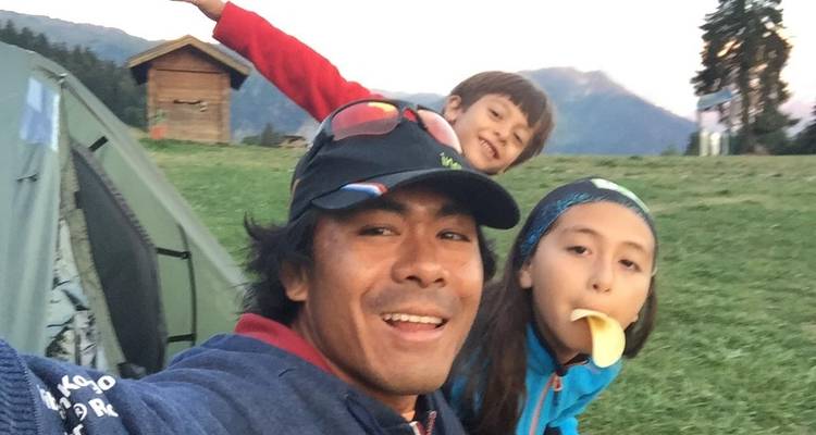 Family posing for a selfie near a tent with scenic background.