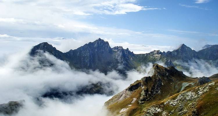 Pics montagneux spectaculaires partiellement couverts par les nuages.