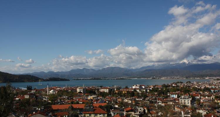 Luftaufnahme einer Küstenstadt mit Bergen in der Ferne.