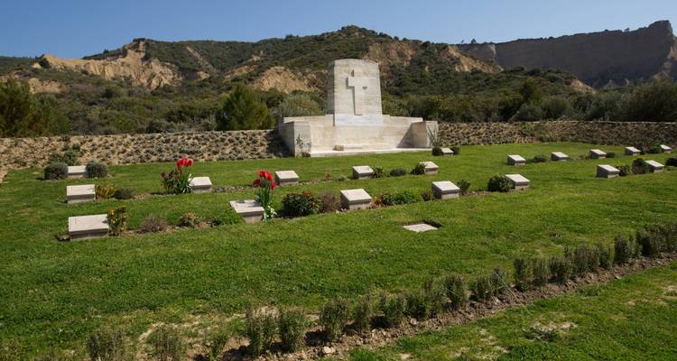 Rangées de simples pierres tombales et une croix de pierre se détachant sur les crêtes escarpées de Gallipoli