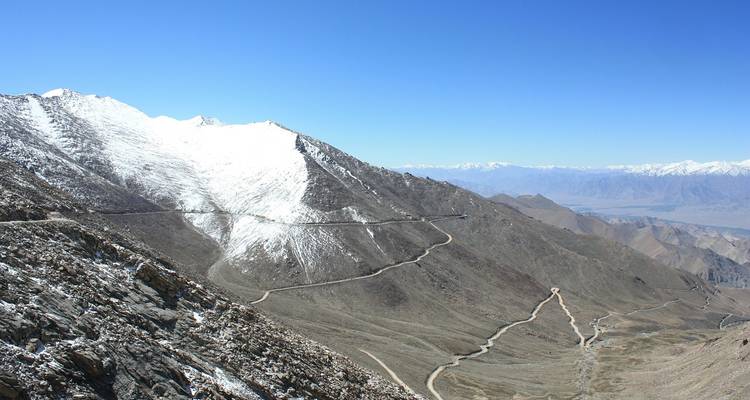 Carretera de montaña serpenteante cubierta de nieve, con vastos paisajes.