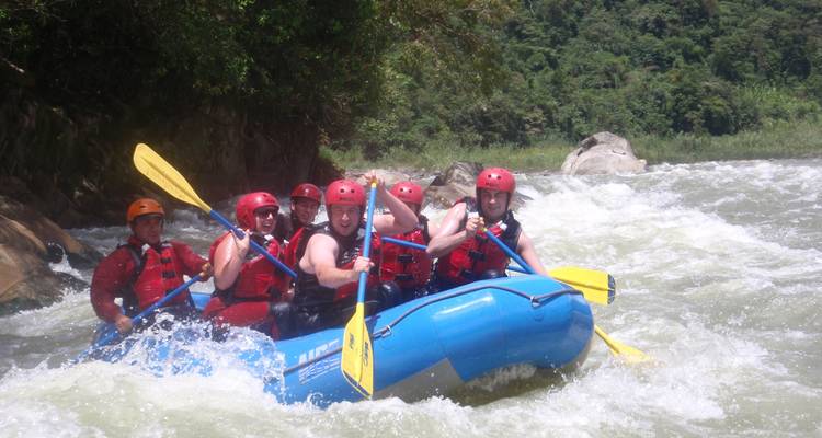 Group of people whitewater rafting in a river.