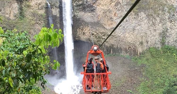 People on a cable car with a waterfall in the background.