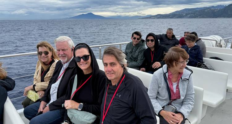 Un groupe de personnes assises sur un bateau avec des montagnes en arrière-plan.
