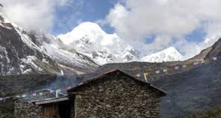 Steingebäude mit Bergen im Hintergrund und Gebetsfahnen.