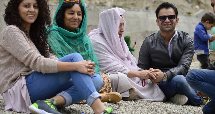Groep mensen die op de grond zitten in traditionele kleding.