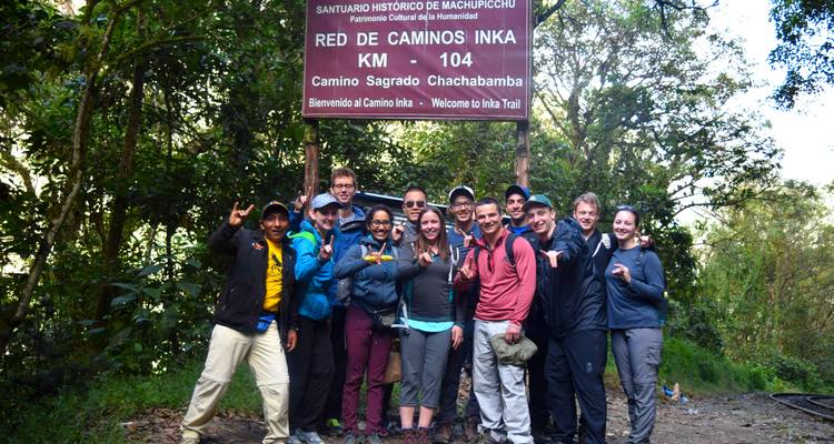 Een vrolijke groep wandelaars die poseert voor een bord op een weelderig pad.