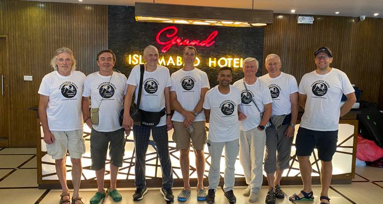Groep mannen in bijpassende shirts staand voor hotelreceptie