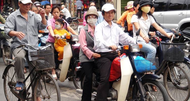 Meerdere motorfietsen met mensen op een drukke straat.
