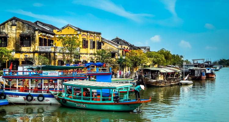 A vibrant riverside scene with boats and historical buildings.