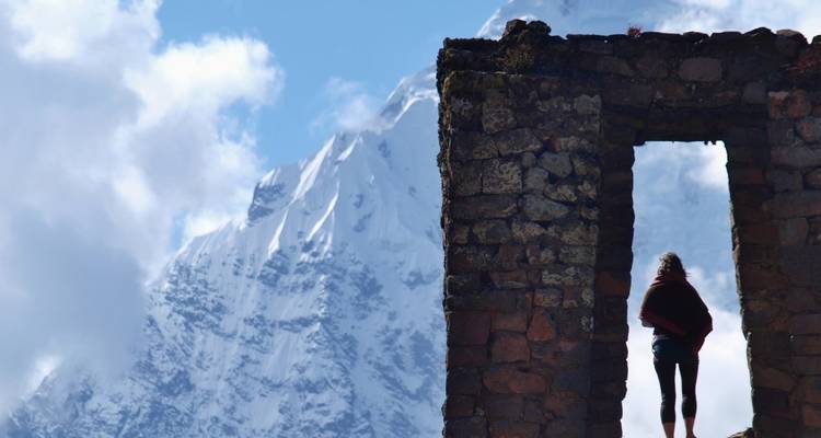Persoon bij oude ruïnes met besneeuwde bergen in de verte