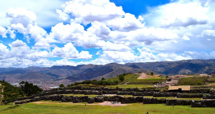 Vue panoramique de prairies avec des ruines antiques et des montagnes.