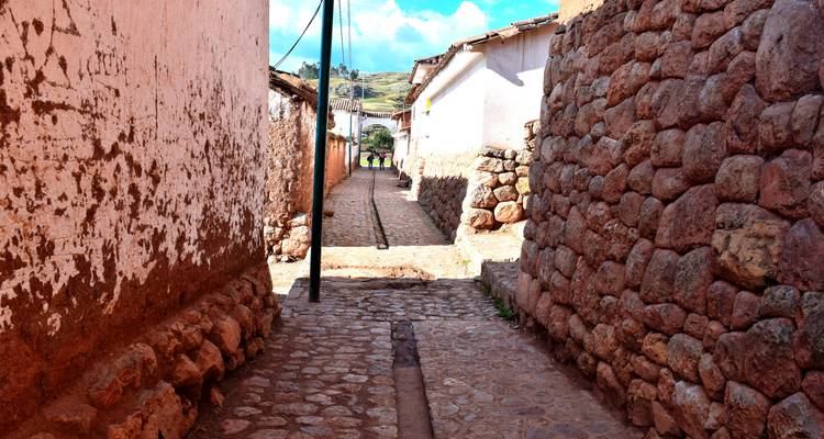Narrow cobblestone alley between stone walls in a rustic town setting.