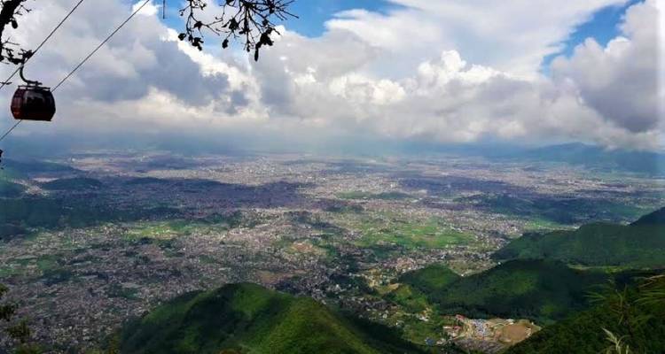 Luftaufnahme einer Talstadt mit bewölktem Himmel und Bergen.