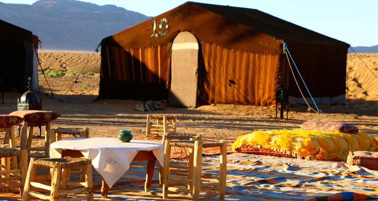 Persoon die loopt op woestijnduinen onder een heldere blauwe hemel.