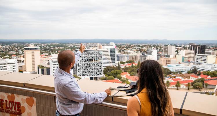 A man pointing out a panoramic city view from a high vantage point.