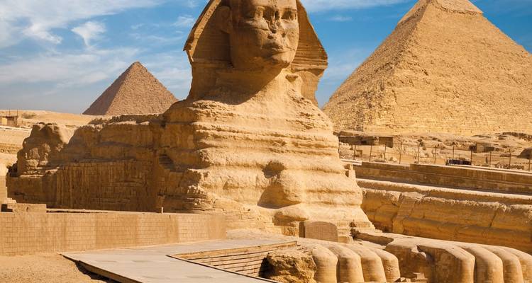 Sphinx with pyramids in the background, depicted under calm skies.