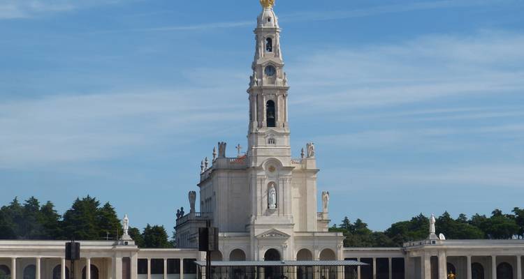 Sacred basilica with a columned facade under a clear blue sky.