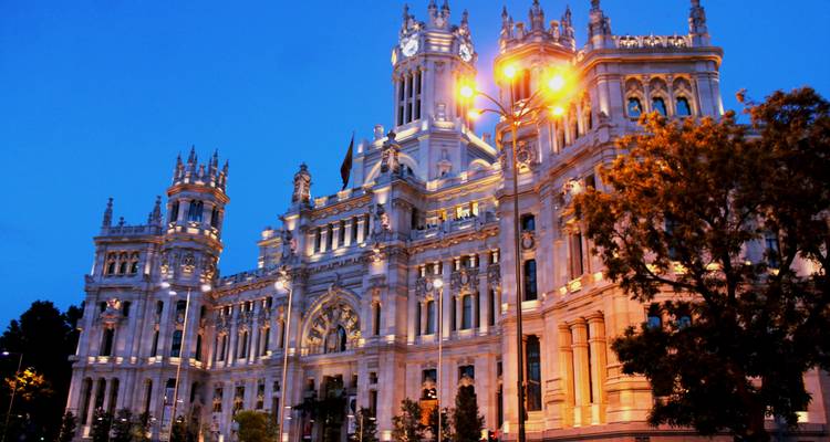 Illuminated historic building at night with surrounding trees.