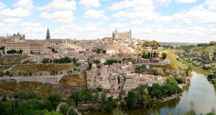 View of a historic cityscape with a river bend and ancient buildings.