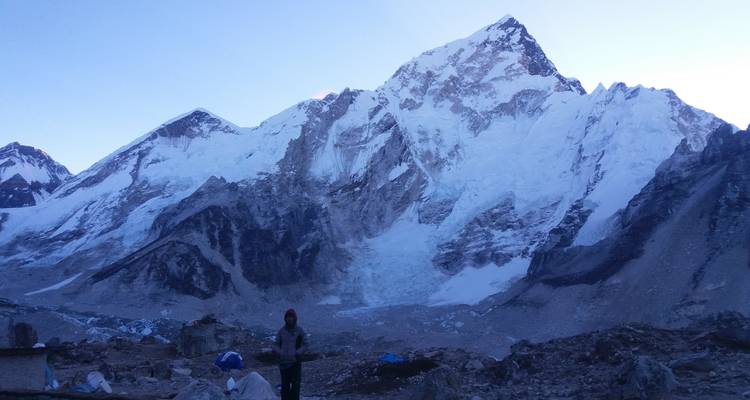 Eine einzelne Person, die vor einer weiten Bergkette steht.