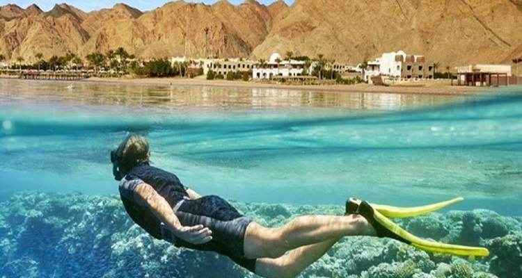 Person, die in klarem Wasser in der Nähe eines Resorts schnorchelt.